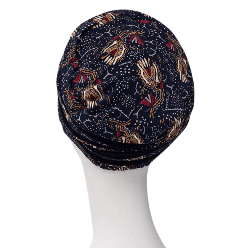 Shanti Turban im Amber Garden Print, von hinten auf weißer Schaufensterpuppe, mit dem dunkelblauen Feder- und Stamm-Motiv
